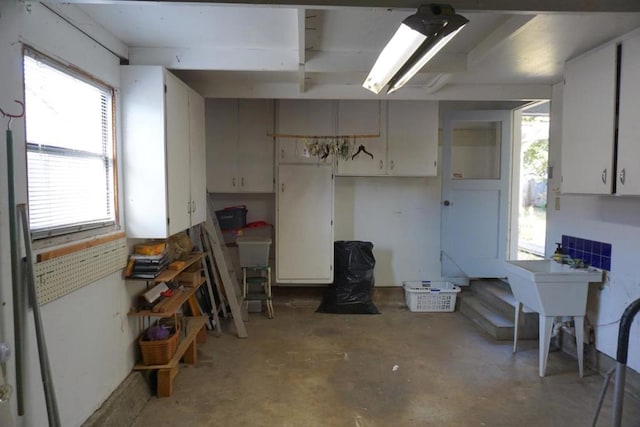 kitchen with a healthy amount of sunlight, concrete floors, and white cabinetry