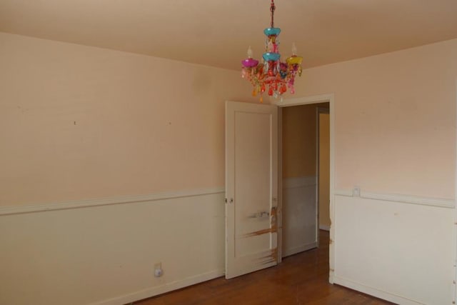 unfurnished room with wood-type flooring and a notable chandelier