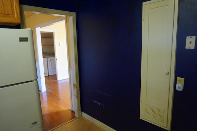 hallway with light wood-type flooring and separate washer and dryer