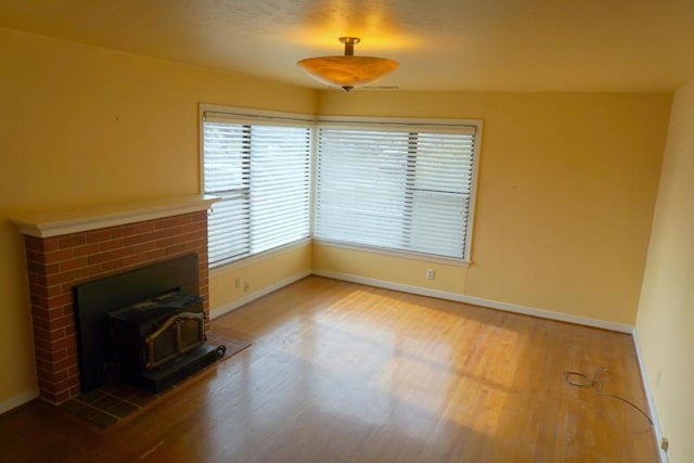 unfurnished living room featuring hardwood / wood-style floors, a wood stove, and plenty of natural light