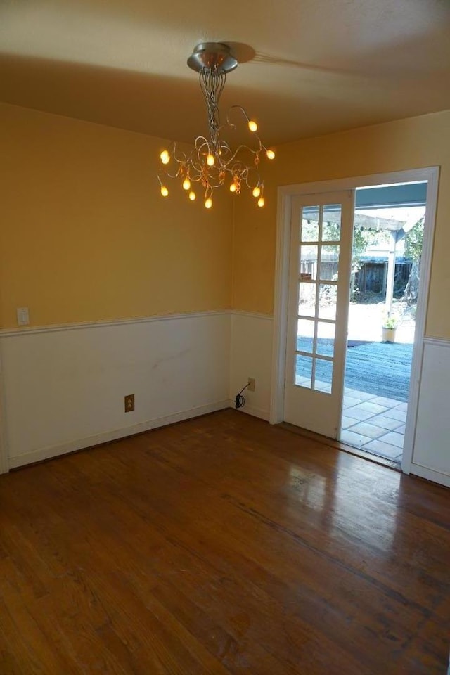 unfurnished room with dark wood-type flooring and a notable chandelier