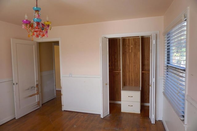 unfurnished bedroom featuring dark hardwood / wood-style flooring and a notable chandelier