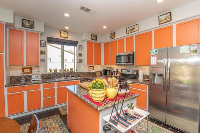 kitchen featuring sink, appliances with stainless steel finishes, a kitchen island, dark tile patterned floors, and dark stone counters