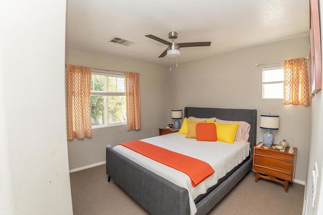 bedroom with multiple windows, light colored carpet, and ceiling fan