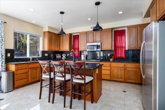 kitchen with backsplash, a kitchen island, hanging light fixtures, and appliances with stainless steel finishes