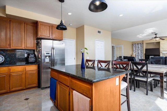 kitchen featuring a center island, hanging light fixtures, tasteful backsplash, stainless steel fridge with ice dispenser, and a breakfast bar