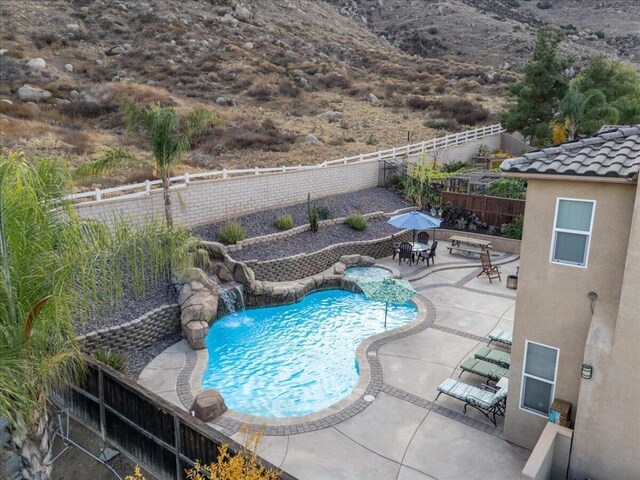 view of swimming pool with pool water feature and a patio