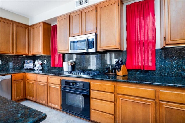 kitchen with light tile patterned floors, stainless steel appliances, tasteful backsplash, and dark stone countertops