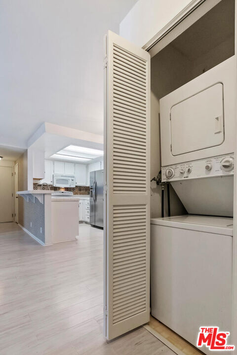 laundry room featuring light wood-type flooring and stacked washer and dryer