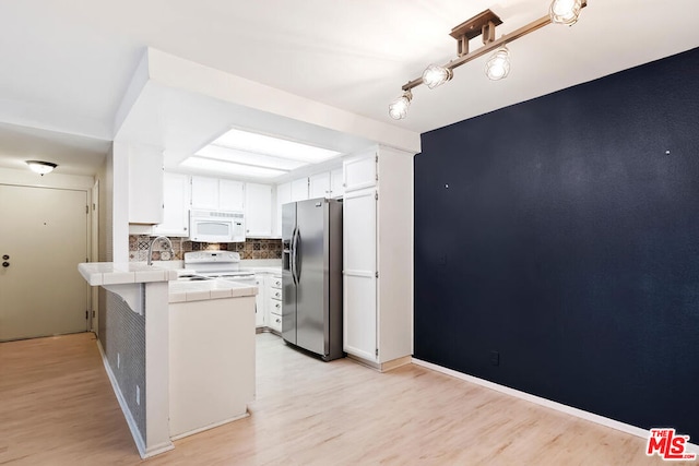 kitchen featuring white appliances, white cabinets, light hardwood / wood-style flooring, tile counters, and kitchen peninsula