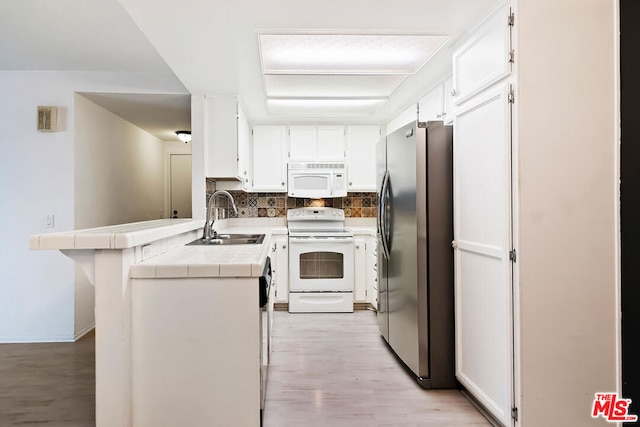 kitchen featuring kitchen peninsula, backsplash, white appliances, sink, and tile countertops