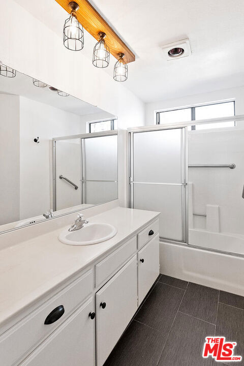 bathroom with vanity and enclosed tub / shower combo