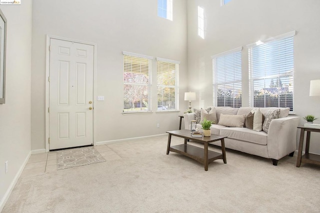 living room with light carpet, a towering ceiling, and a healthy amount of sunlight