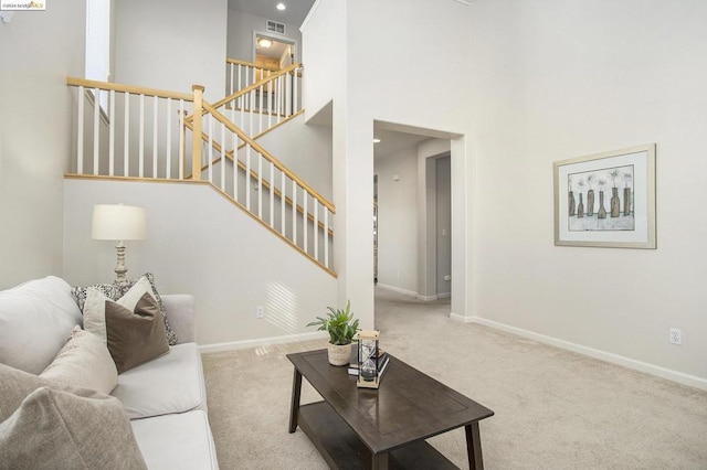 living room with a towering ceiling and light colored carpet