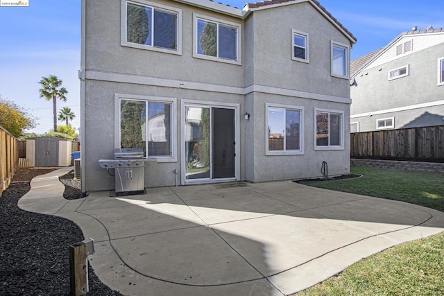 rear view of property featuring a storage unit, a patio, and a lawn