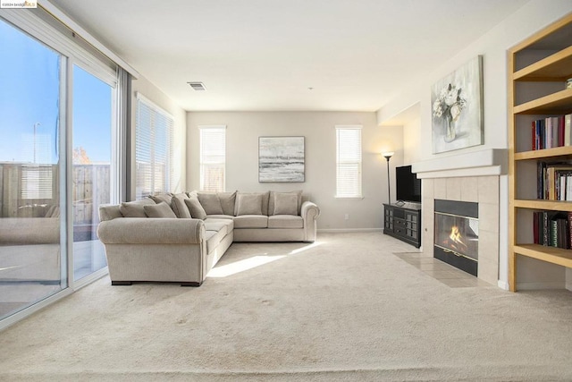 living room featuring a tile fireplace and light carpet