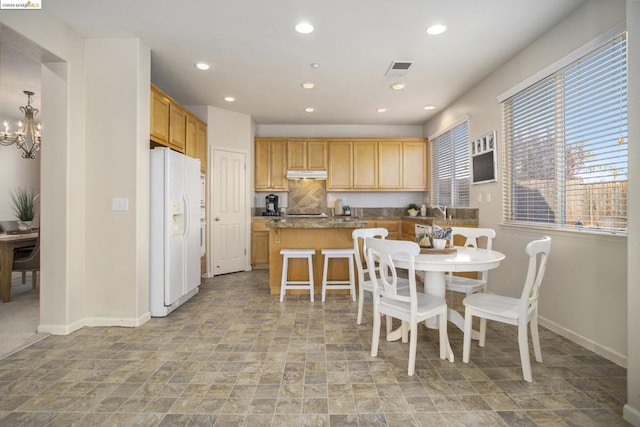 interior space with a chandelier, a kitchen breakfast bar, a center island, white fridge with ice dispenser, and light stone counters