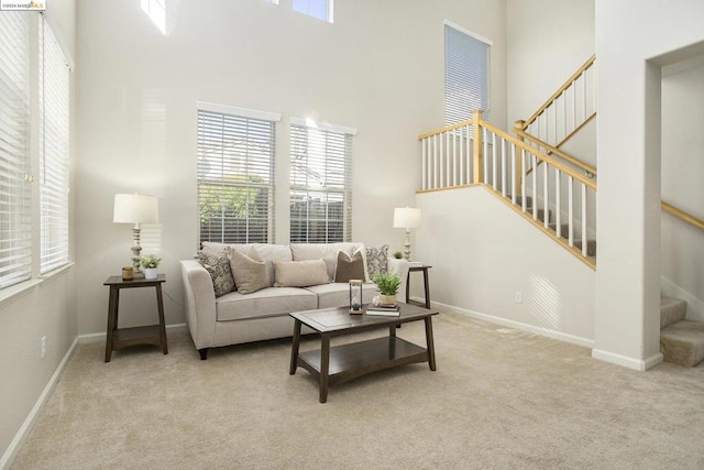 carpeted living room featuring a towering ceiling