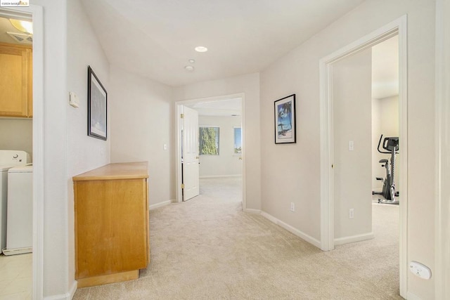 corridor featuring washer / clothes dryer and light colored carpet