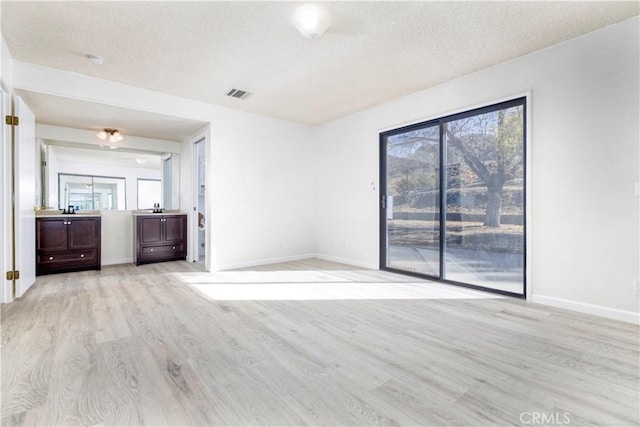 empty room featuring a textured ceiling and light wood-type flooring