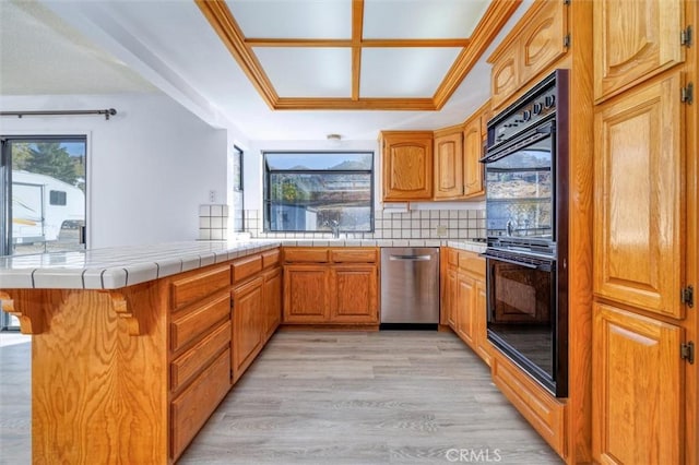 kitchen with kitchen peninsula, black double oven, tile countertops, dishwasher, and light hardwood / wood-style floors