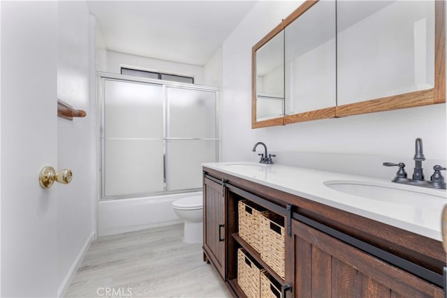 full bathroom with hardwood / wood-style floors, toilet, combined bath / shower with glass door, and vanity