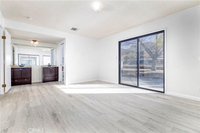 spare room featuring a textured ceiling and light wood-type flooring