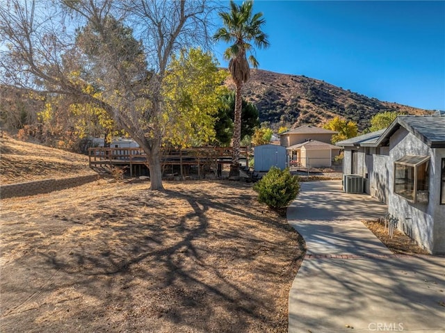 view of front of property with a storage unit, cooling unit, and a deck with mountain view