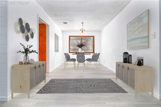 interior space with a notable chandelier, light hardwood / wood-style floors, and a textured ceiling