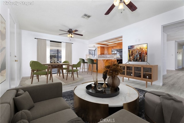 living room featuring a textured ceiling, light hardwood / wood-style floors, and ceiling fan