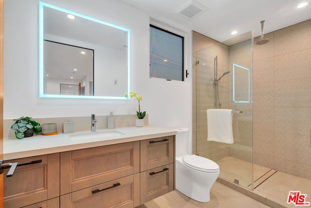 bathroom with a tile shower, tile patterned flooring, vanity, and toilet