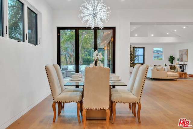 dining space with light hardwood / wood-style floors and a notable chandelier