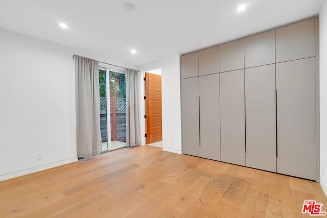 unfurnished bedroom with access to outside and light hardwood / wood-style floors