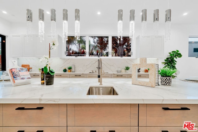 kitchen with pendant lighting, light stone counters, and sink