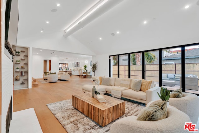 living room with beamed ceiling, light hardwood / wood-style floors, and high vaulted ceiling