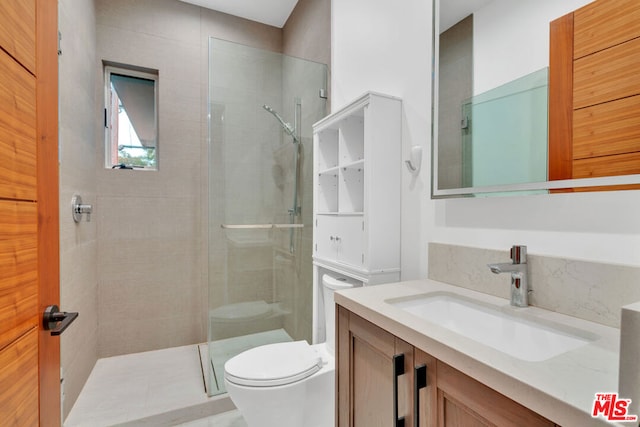 bathroom with tiled shower, vanity, and toilet