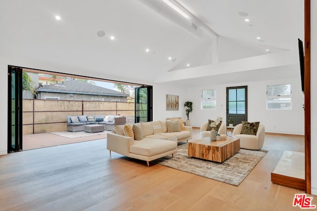 living room featuring beamed ceiling, high vaulted ceiling, and light hardwood / wood-style flooring