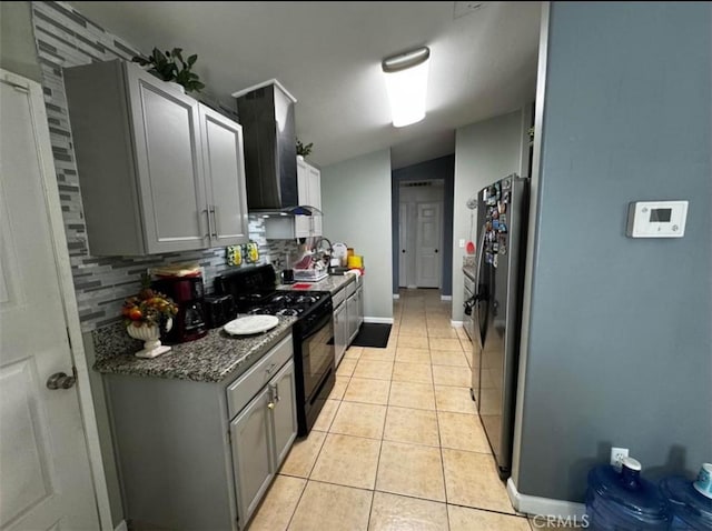 kitchen with black stove, light tile patterned floors, wall chimney range hood, fridge, and tasteful backsplash