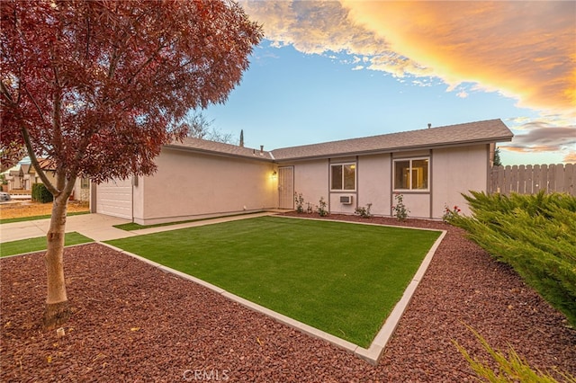 back house at dusk with a lawn and a garage