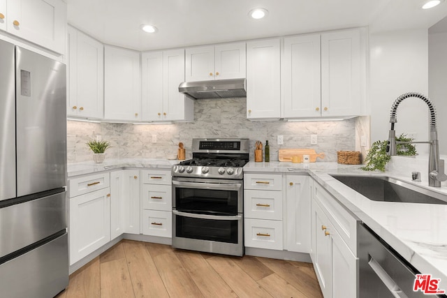 kitchen featuring sink, stainless steel appliances, light stone counters, and white cabinets