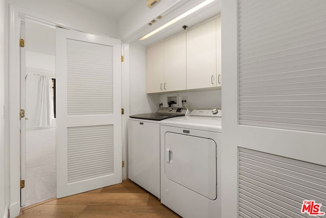 washroom with light wood-type flooring, cabinets, and independent washer and dryer