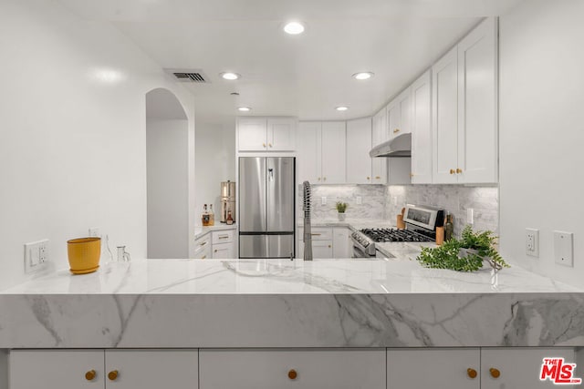 kitchen with light stone counters, decorative backsplash, white cabinets, and stainless steel appliances