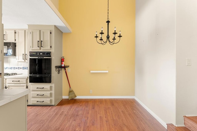 kitchen with pendant lighting, an inviting chandelier, gas stovetop, tile counters, and light hardwood / wood-style floors