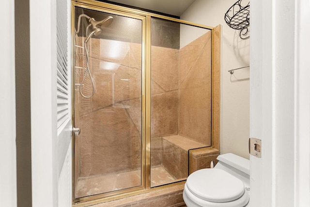 bathroom featuring a shower with door and toilet