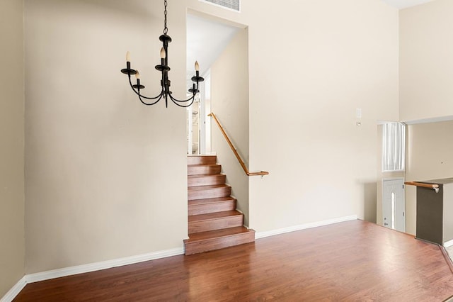 stairs with hardwood / wood-style floors and a chandelier