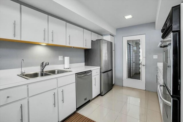 kitchen featuring appliances with stainless steel finishes, light tile patterned floors, white cabinetry, and sink