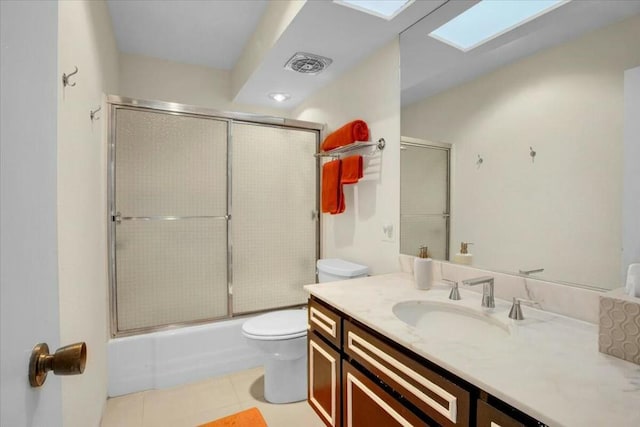 full bathroom featuring a skylight, tile patterned floors, vanity, shower / bath combination with glass door, and toilet