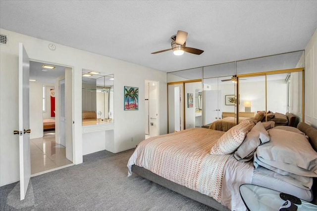 bedroom with carpet, ceiling fan, and two closets