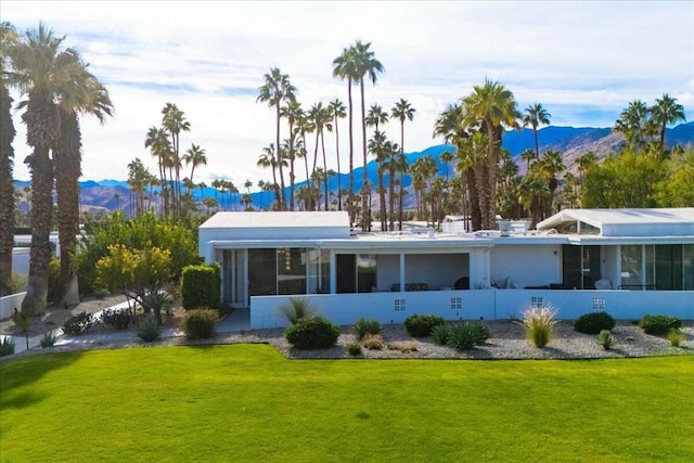 back of property featuring a lawn, a sunroom, and a mountain view