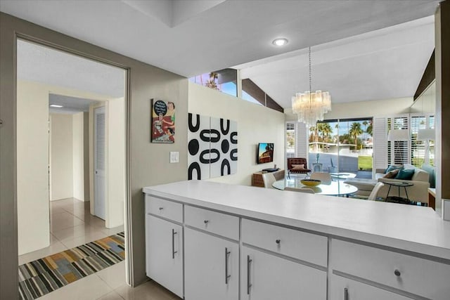 kitchen with white cabinetry, a notable chandelier, lofted ceiling, decorative light fixtures, and light tile patterned floors